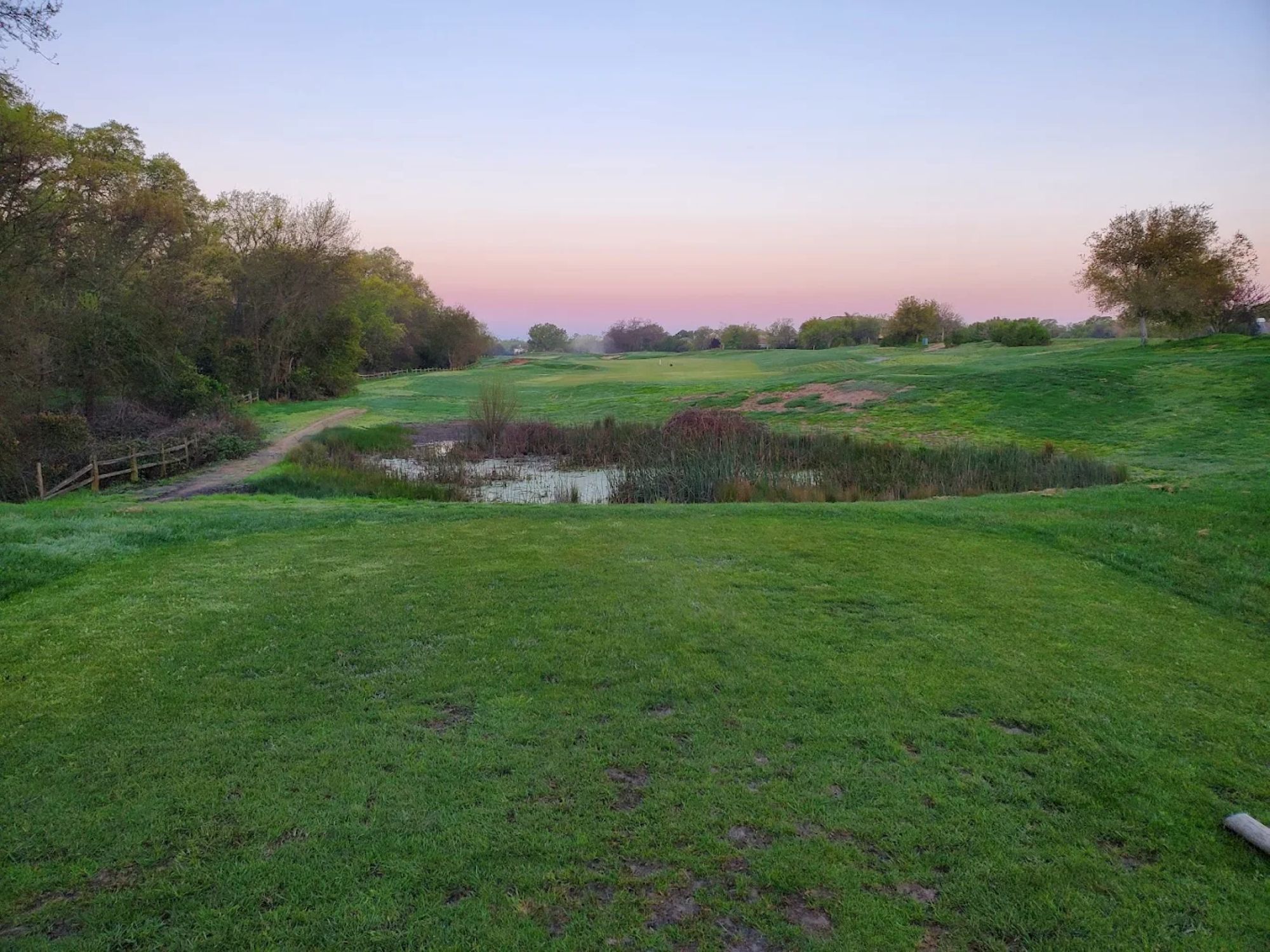 Golf course fairway with pond at sunset